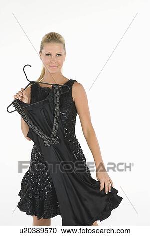 Stock Image - Woman holds black dress in front of her. Fotosearch