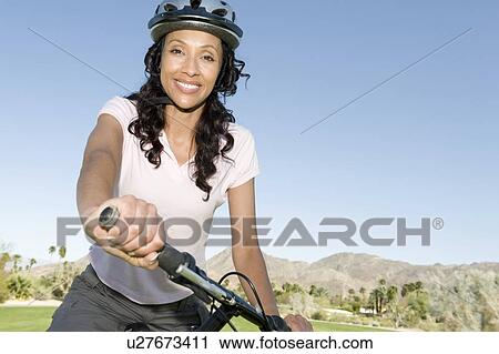 Stock Image - Woman in cycling helmet holds handlebars of mountainbike. Fotosearch