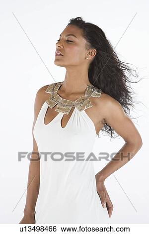 Stock Photograph - Woman in white dress stands with hand on hip. Fotosearch