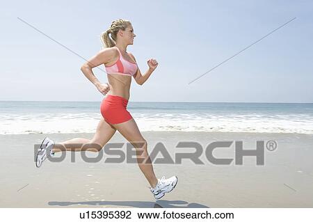 Woman jogging along beach View Large Photo Image Stock Image - Woman jogging along beach. Fotosearch