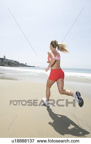 Stock Photo - Woman jogging along beach. Fotosearch