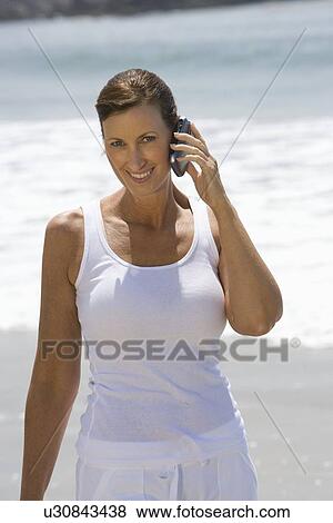 Stock Photo - Woman on mobile phone at the beach. Fotosearch
