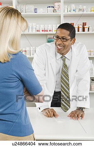 Picture - Woman picking up prescription drugs at pharmacy. Fotosearch