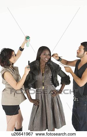 Stock Photo - Woman stands in fur jacket with stylists on hand. Fotosearch