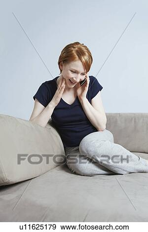 Stock Photo - Woman talking on mobile phone on sofa. Fotosearch