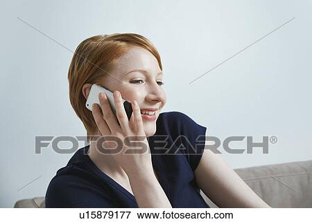 Stock Photo - Woman talking on mobile phone on sofa. Fotosearch