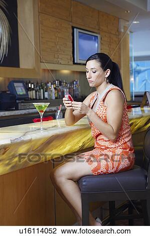 Stock Image - Woman Text Messaging at a Bar. Fotosearch
