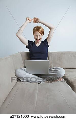 Stock Image - Woman using laptop on sofa. Fotosearch