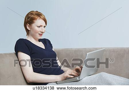 Woman using laptop on sofa View Large Photo Image Stock Photo - Woman using laptop on sofa. Fotosearch