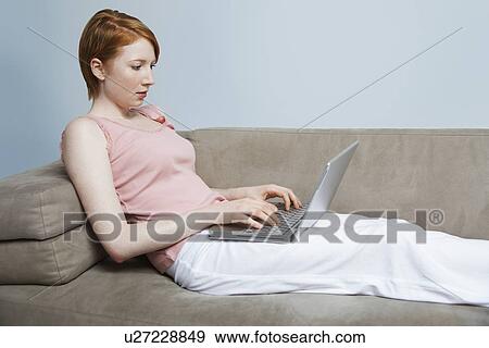 Stock Photo - Woman using laptop on sofa. Fotosearch