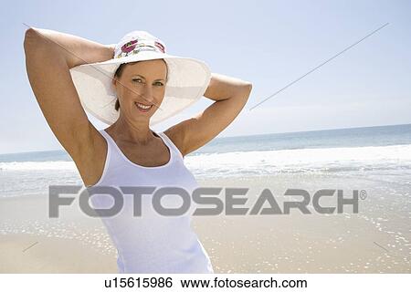 Stock Photograph - Woman wearing sunhat on beach. Fotosearch