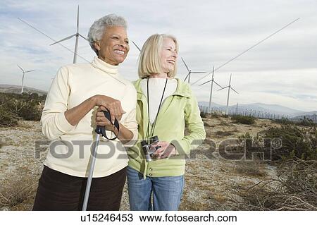 Stock Image - Women hiking near wind farm. Fotosearch