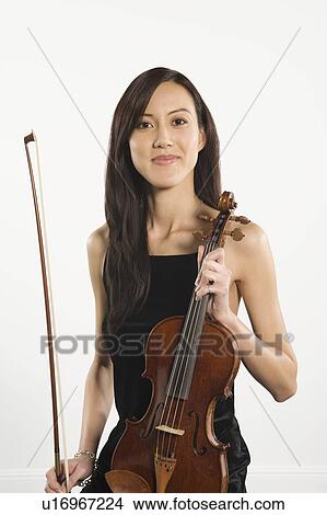 Young Asian woman sits holding a violin View Large Photo Image Picture - Young Asian woman sits holding a violin. Fotosearch