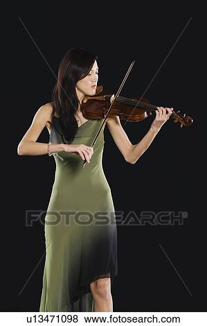 Stock Photo - Young Asian woman stands playing the violin. Fotosearch