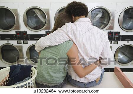 Picture - Young couple washing clothes at launderette. Fotosearch