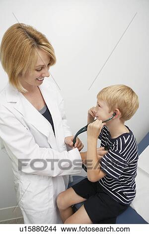 Picture - Young female doctor examining boy, elevated view. Fotosearch