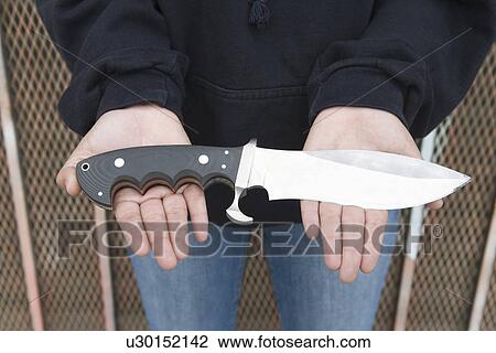 Stock Image - Young man holding knife on her palms. Fotosearch
