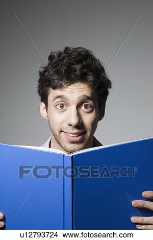 Young man smiling over book cover View Large Photo Image Picture - Young man smiling over book cover. Fotosearch