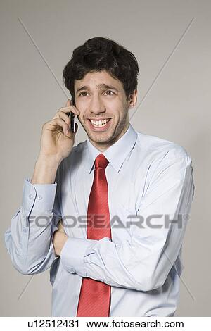 Stock Image - Young man talking on mobile phone, studio shot. Fotosearch