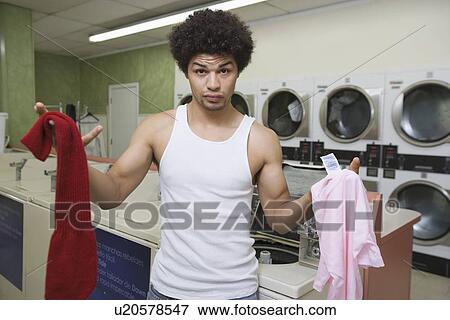 Young man washing clothes at launderette View Large Photo Image Stock Photo - Young man washing clothes at launderette. Fotosearch