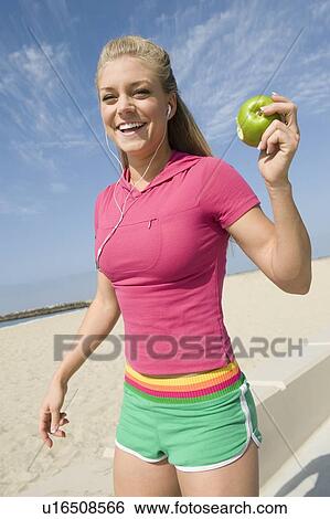 Stock Photograph - Young woman holding apple. Fotosearch