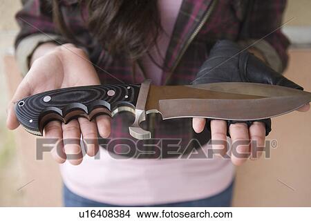 Picture - Young woman holding knife on her palms. Fotosearch