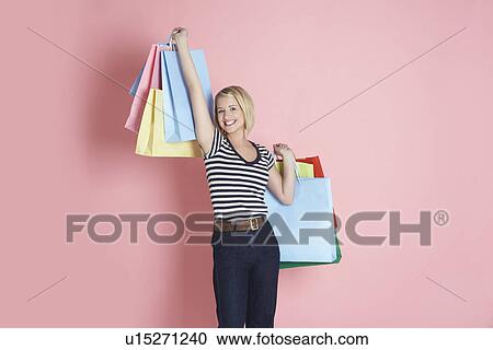 Stock Image - Young woman holding shopping bags and smiling. Fotosearch