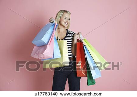 Young woman holding shopping bags and smiling View Large Photo Image Stock Image - Young woman holding shopping bags and smiling. Fotosearch