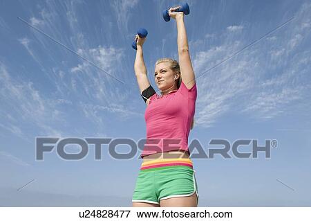 Stock Photo - Young woman lifting hand weights. Fotosearch