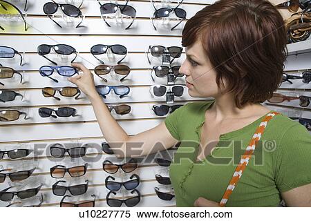 Stock Photography - Young woman shopping for glasses. Fotosearch