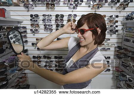 Stock Photography - Young woman shopping for sunglasses. Fotosearch