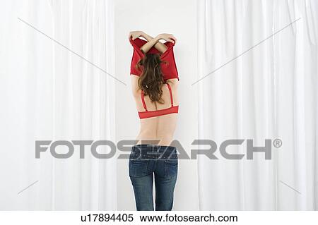Young woman undressing in fitting room View Large Photo Image Stock Photography - Young woman undressing in fitting room. Fotosearch