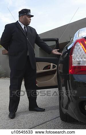 Stock Image - Chauffeur extends hand to client in luxury vehicle. Fotosearch