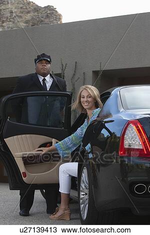 Chauffeur helps woman from luxury vehicle View Large Photo Image Stock Image - Chauffeur helps woman from luxury vehicle. Fotosearch
