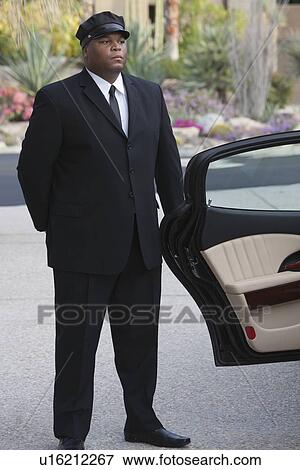 Chauffeur stands at open car door of luxury vehicle View Large Photo Image Stock Photo - Chauffeur stands at open car door of luxury vehicle. Fotosearch