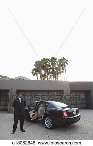Chauffeur stands at open car door of luxury vehicle View Large Photo Image Stock Photo - Chauffeur stands at open car door of luxury vehicle. Fotosearch