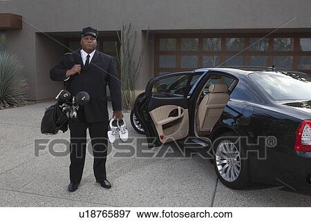 Chauffeur stands with golf equipment near luxury vehicle View Large Photo Image Stock Photo - Chauffeur stands with golf equipment near luxury vehicle. Fotosearch