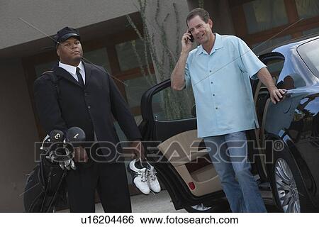 Chauffeur stands with golf equipment and owner of luxury vehicle View Large Photo Image Stock Photograph - Chauffeur stands with golf equipment and owner of luxury vehicle. Fotosearch