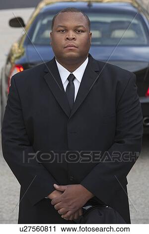Chauffeur stands wth hands clasped near luxury vehicle View Large Photo Image Stock Image - Chauffeur stands wth hands clasped near luxury vehicle. Fotosearch