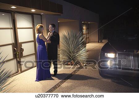 Stock Image - Couple say goodbyes at lit building exterior. Fotosearch