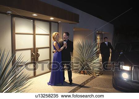 Stock Photography - Couple say goodbyes at lit building exterior. Fotosearch