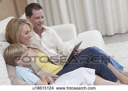 Family of three sit reading a digital book View Large Photo Image Picture - Family of three sit reading a digital book. Fotosearch