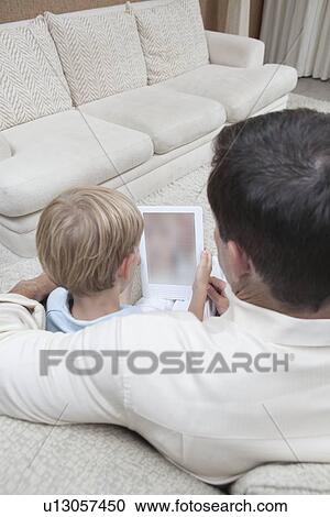 Stock Image - Father and son read a digital book. Fotosearch