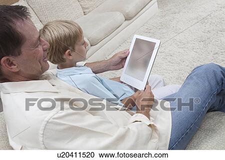 Father and son read a digital book View Large Photo Image Stock Image - Father and son read a digital book. Fotosearch