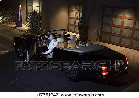 Stock Image - Man leaving building in convertible car. Fotosearch