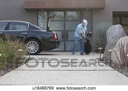 Man lifting golf bag into boot of luxury vehicle View Large Photo Image Stock Photo - Man lifting golf bag into boot of luxury vehicle. Fotosearch
