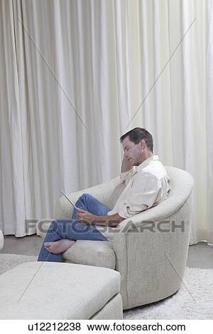 Man sits reading a digital book View Large Photo Image Stock Photo - Man sits reading a digital book. Fotosearch
