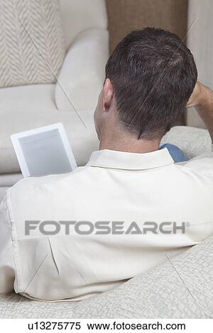 Man sits reading a digital book View Large Photo Image Stock Photography - Man sits reading a digital book. Fotosearch