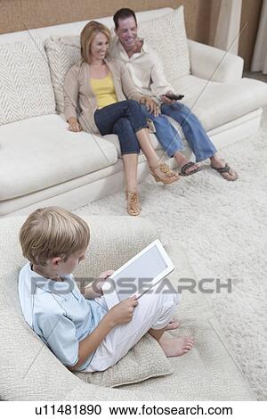Parents watch television while son reads a digital book View Large Photo Image Stock Image - Parents watch television while son reads a digital book. Fotosearch