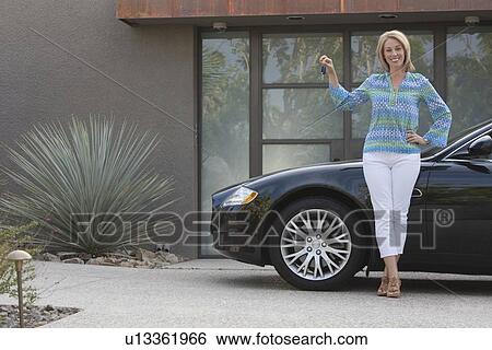 Stock Photograph - Woman stands holding keys to luxury vehicle. Fotosearch
